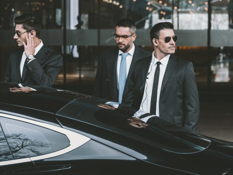 bodyguards going with businessman and reviewing territory near car