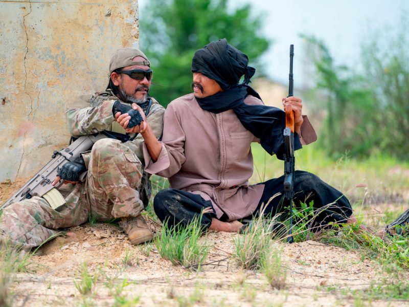 Man with veil shake hand with military or soldier in battle field look like they join as teamwork for fighting.